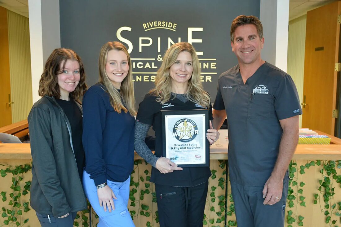 Riverside Spine and Physical Medicine staff holding the Clarksville's Best award in front of the clinic sign