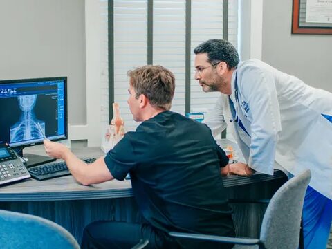 Riverside providers reviewing a patient's spinal X-ray on screen